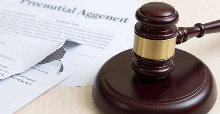 Gavel striking block near torn prenuptial agreement